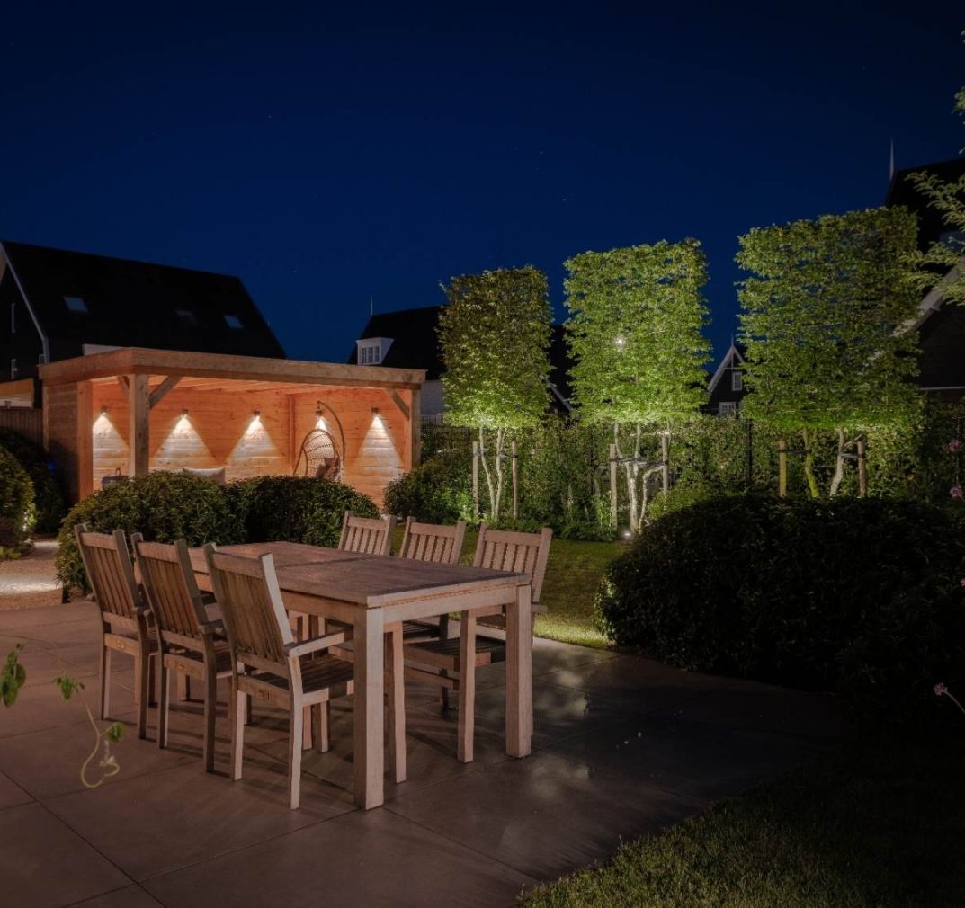 Luxe verlichte achtertuin met terras, tuin en overkapping