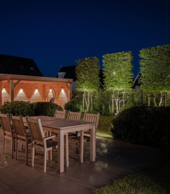 Luxe verlichte achtertuin met terras, tuin en overkapping