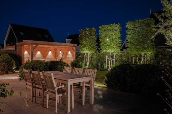 Luxe verlichte achtertuin met terras, tuin en overkapping