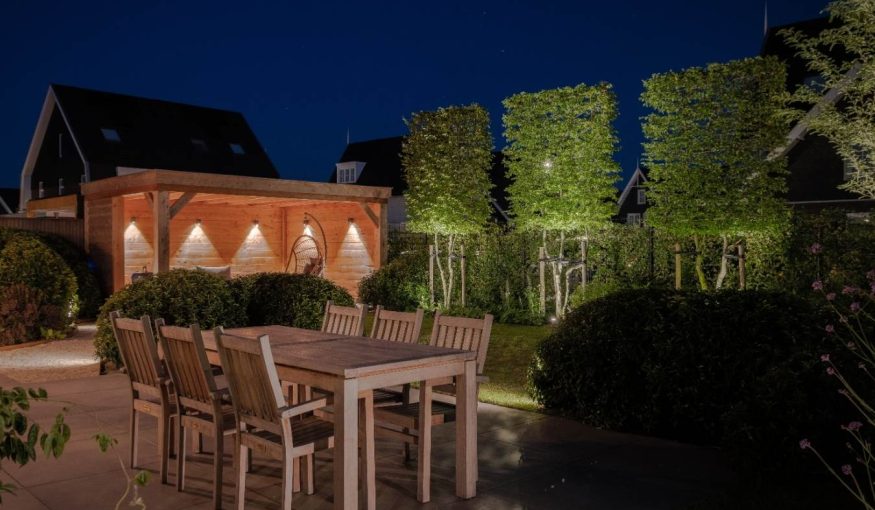 Luxe verlichte achtertuin met terras, tuin en overkapping