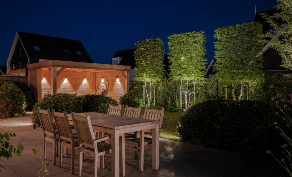 Luxe verlichte achtertuin met terras, tuin en overkapping