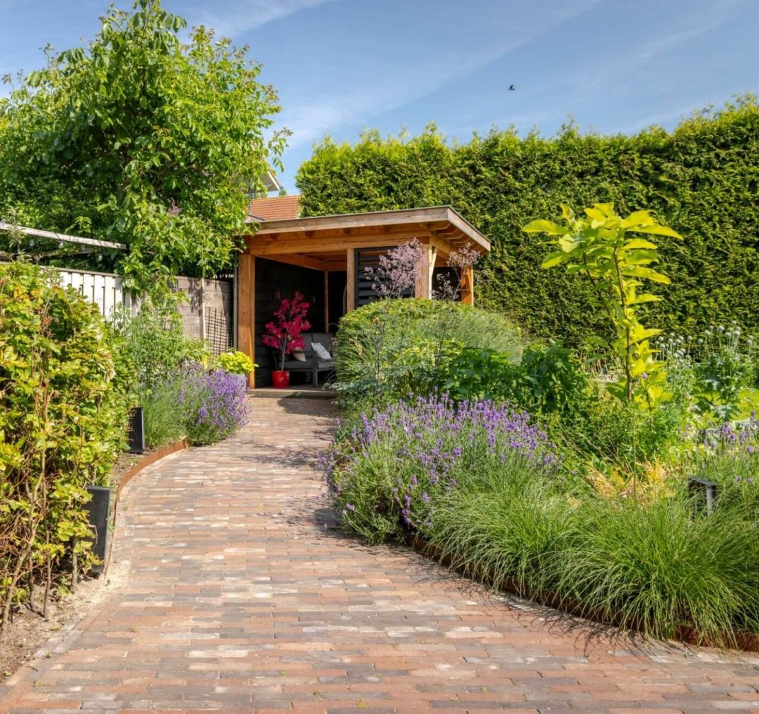 Achtertuin met overkapping, een looppad en vollop groen